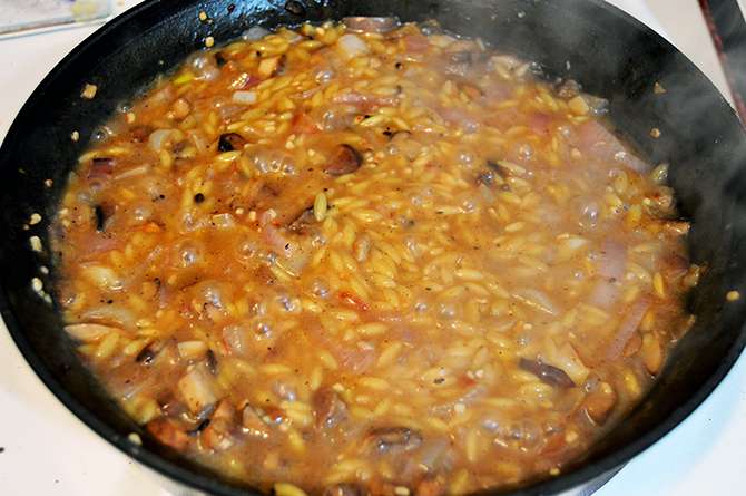 cooking orzo in a pan with mushrooms