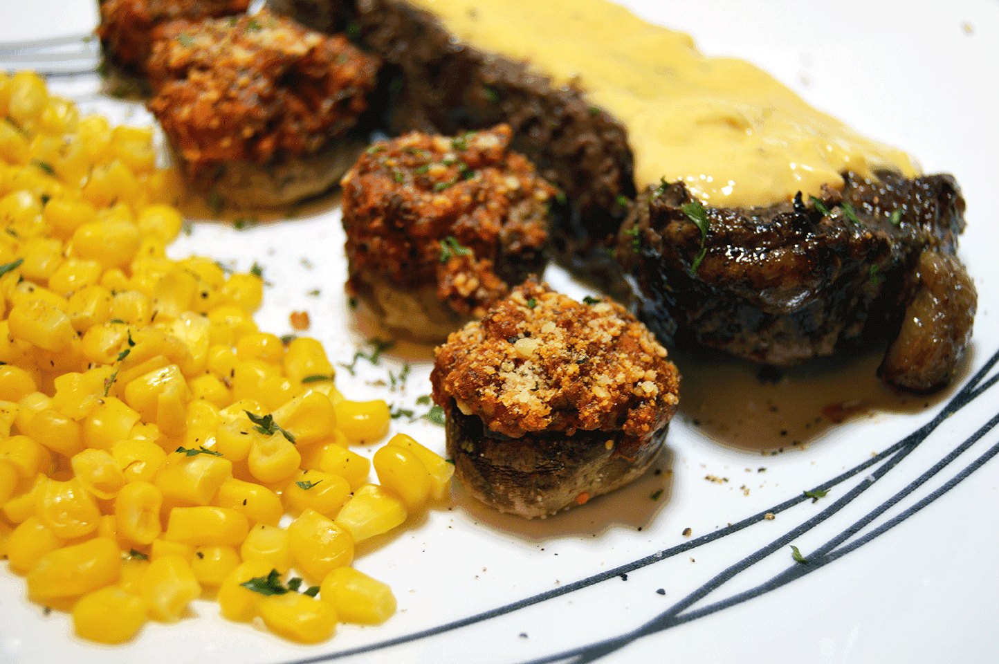 stuffed mushrooms on a plate with steak and corn