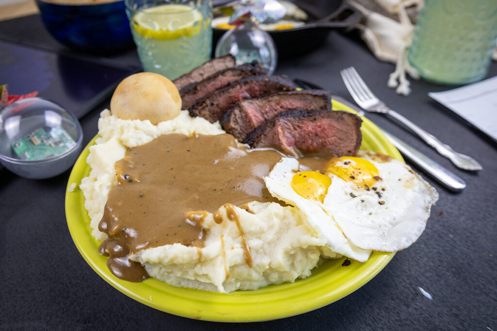 mashed potatoes and gravy on a plate with steak and eggs inspired by twister