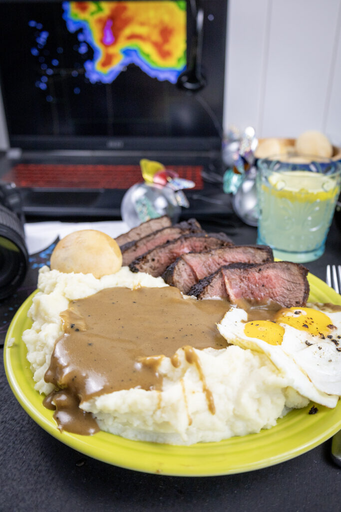 radar in the background showing a tornado with steak, eggs and mashed potates and gravy in the foreground